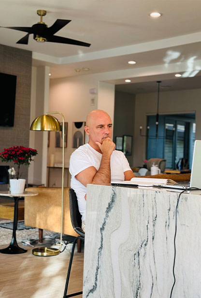 A man seated at a desk, working in front of a sleek marble counter.